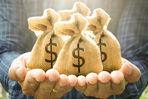 a man holding four small bags with money signs on them