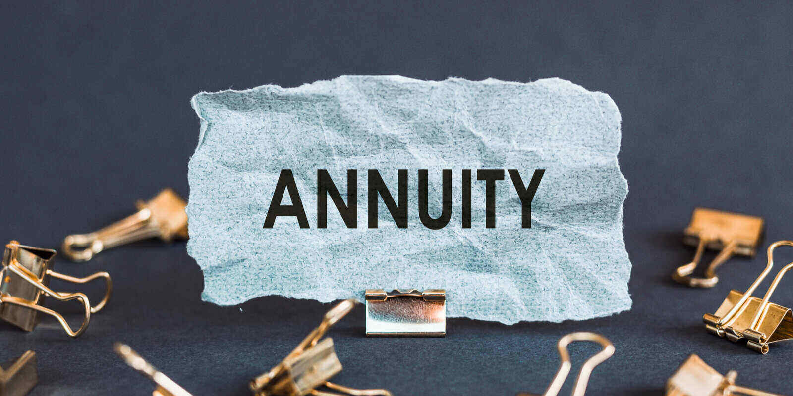 scrap of blue paper with clips on a gray background with the text annuity