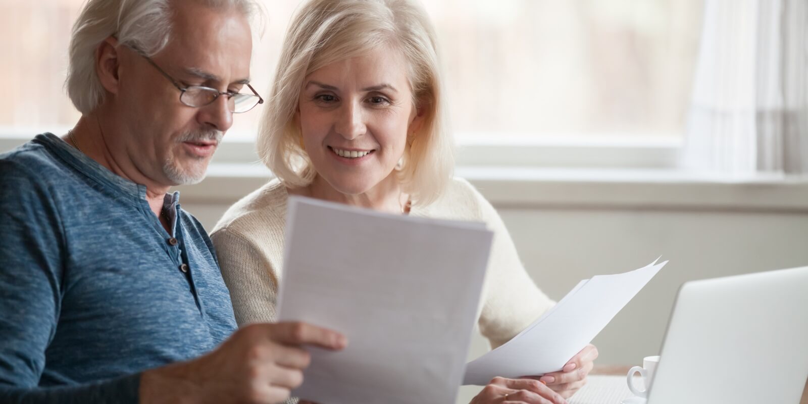 old middle aged couple holding reading good news in document