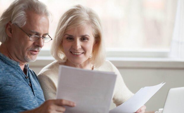 middle aged couple holding reading good news in document