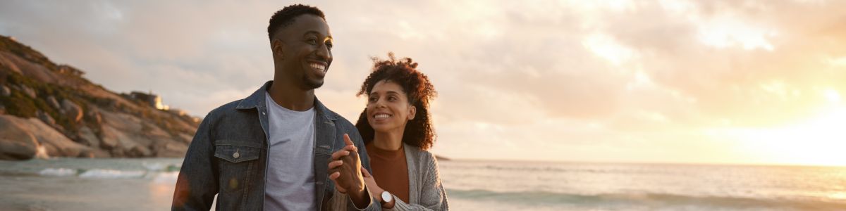 Two People Walking The Beach In The Evening