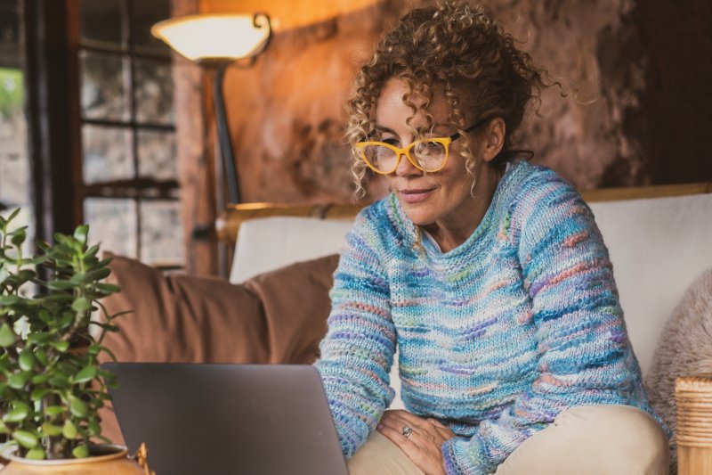 Woman Sitting On Her Couch Researching Retirement Income Planning Services