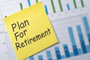 Sticky Note with Plan for Retirement Text Over Financial Graphs