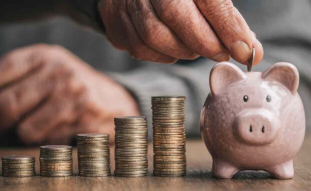 Hand Putting Coin in Piggy Bank Saving Money for Retirement Investment