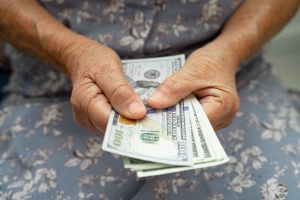 Senior Woman Holding UA Dollar After Withdrawing from Annuity Funds