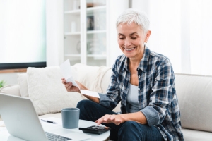 Smiling Senior Woman Calculating MYGA Returns Using Calculator