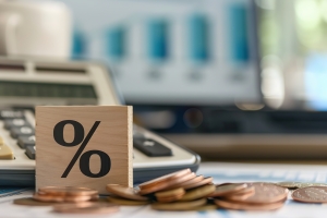 Percent Sign on Wooden Block Near Calculator and Coins Showing Tax Difference Between Investments